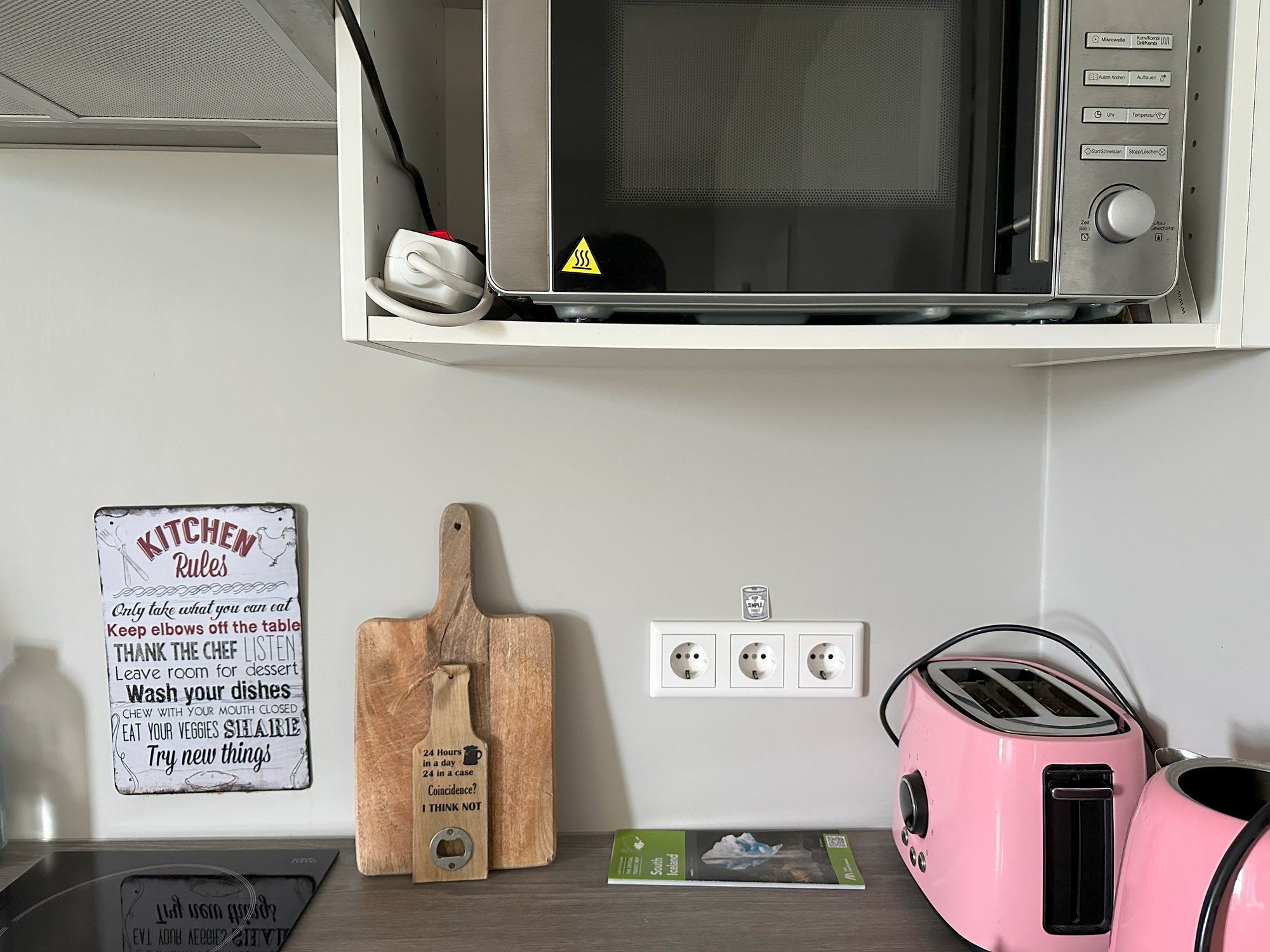 A kitchen counter with a heuristics postcard propped near a pink toaster