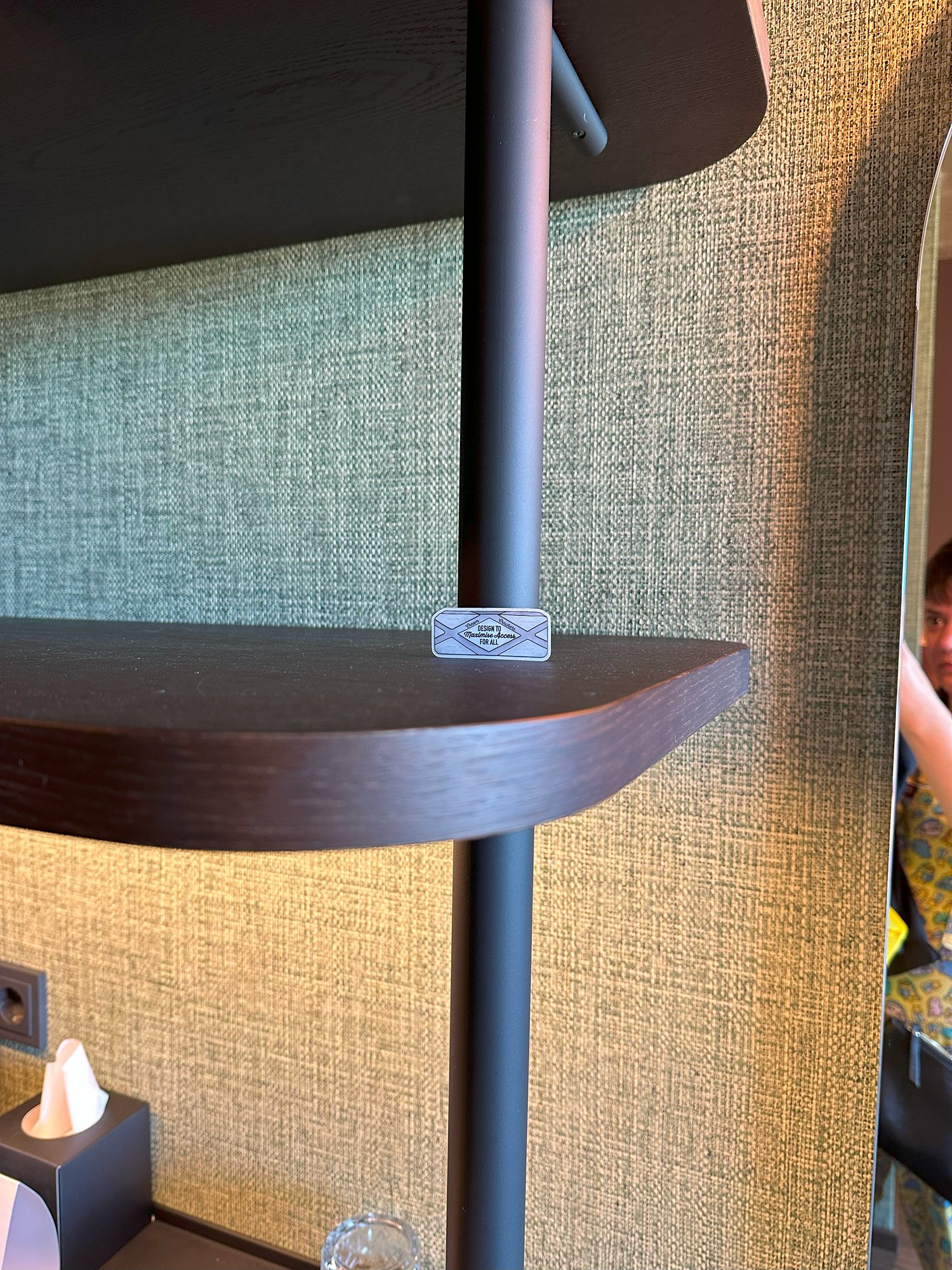 A heuristic sticker on a wooden shelf bracket in a hotel room